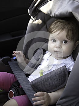 Cute little baby sits fastened in a child car seat ready for a ride. Child safety concept