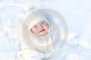 Cute little baby sitting in fresh winter snow