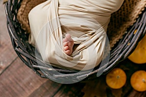 Cute little baby sleeping in a wicker basket of twigs with yellow leaves