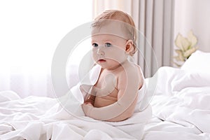 Cute little baby with soft towel on bed after bath