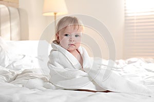 Cute little baby with soft towel on bed after bath