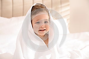 Cute little baby with soft towel on bed after bath