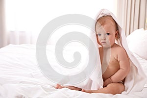 Cute little baby with soft towel on bed after bath. Space for text