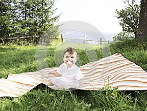 Cute little baby with a soother on the meadow in summer day