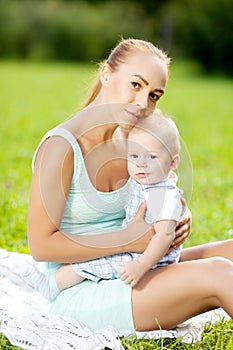 Cute little baby in summer park with mother on the grass. Swee