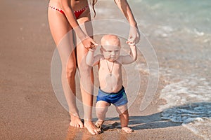 Cute little baby walking along the seaside with his sister