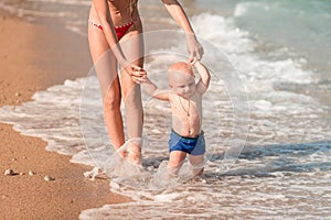 Cute little baby walking along the seaside with his sister