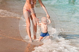 Cute little baby walking along the seaside with his sister