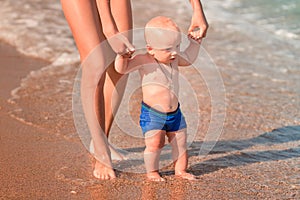 Cute little baby walking along the seaside with his sister