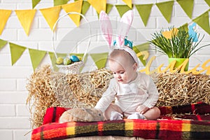 Cute little baby wearing bunny ears on Easter day and stroking r