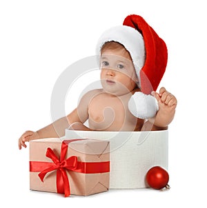 Cute little baby wearing Santa hat sitting in box with Christmas gift on white