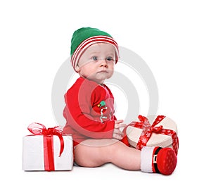 Cute little baby wearing Santa`s elf clothes with Christmas gifts on white background