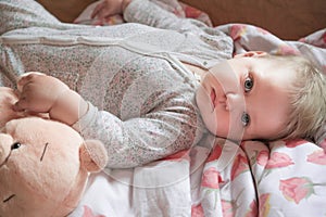 A cute little baby is woke up and lies on the bed, calm and pacified photo