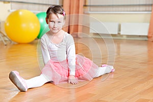 Cute little balerina stretching on floor