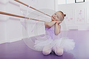 Cute little ballerina girl exercising at dance school