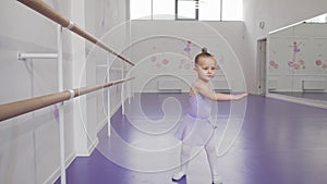 Cute little ballerina in leotard whirling in dance at ballet school
