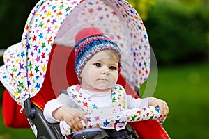 Cute little beautiful baby girl of 6 months sitting in the pram or stroller and waiting for mom