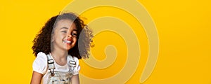 Cute little black girl sincerely laughing over yellow background, long panorama