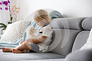 Cute little blond child, toddler boy, playing with white puppy maltese dog