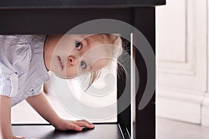 Cute little blond girl in striped shirt climbed in recess table