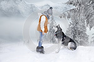 Cute little blonde girl playing in the snow with a dog Husky