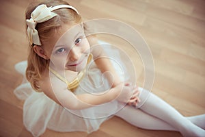 Cute little blonde girl sitting in ballet tutu