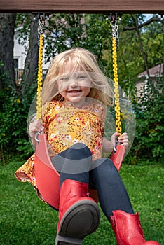 Cute little blonde girl swinging in the backyard