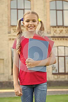 Cute little bookworm. Cute smiling small child hold books educational institution background. Adorable little girl
