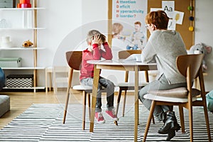 Cute little boy with ADHD during session with professional therapist photo