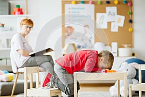 Cute little boy with ADHD during session with professional therapist photo