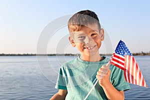 Cute little boy with American flag near river