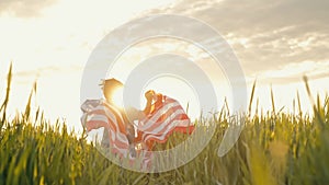 Cute little boy - American patriot kid running with national flag in green field.USA, 4th of July - Independence day