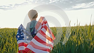 Cute little boy - American patriot kid running with national flag in green field.USA, 4th of July - Independence day