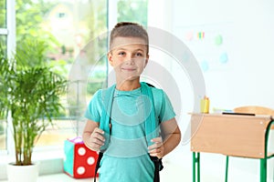 Cute little boy with backpack in classroom