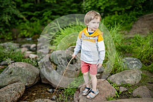 Cute little boy with a backpack having fun outdoors on sunny summer day. Child exploring nature. Kid going on a trip