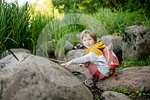 Cute little boy with a backpack having fun outdoors on sunny summer day. Child exploring nature. Kid going on a trip