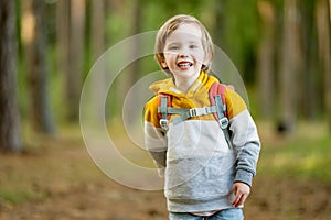 Cute little boy with a backpack having fun outdoors on sunny summer day. Child exploring nature. Kid going on a trip