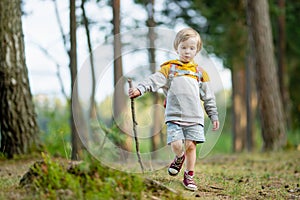 Cute little boy with a backpack having fun outdoors on sunny summer day. Child exploring nature. Kid going on a trip