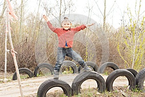 Cute little boy balanced on old tyres