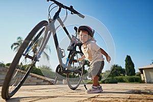 cute little boy with big bike outdoors in city street