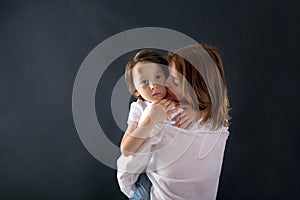 Cute little boy with big bump on his forehead from falling, hugging his mom