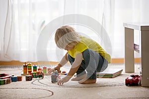 Cute little boy, blond child, playing with colorful cubes with letters and numbers