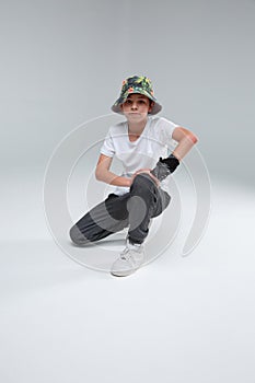 A cute little boy, break dancer, sits in a dance pose on one knee.