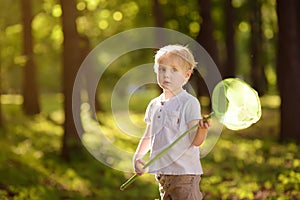 Cute little boy catches butterflies with scoop-net on sunny meadow.Study of nature. Young naturalist