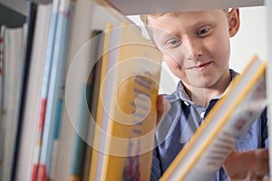 Cute little boy choose a book on the bookshelf