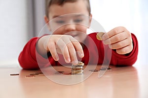 Cute little boy with coins at home. Counting money