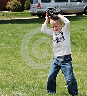 Cute little boy covering his head with baseball glove