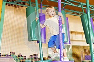 Cute little boy crawling and playing on colorful playground at amusement park