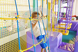 Cute little boy crawling and playing on colorful playground at amusement park