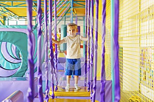 Cute little boy crawling and playing on colorful playground at amusement park